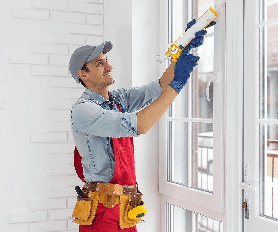 Man using caulking gun on window